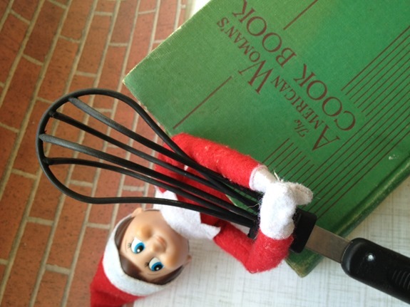 Elf on the Shelf baking with a whisk and cookbook