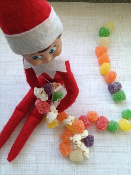 Elf on the Shelf making a gumdrop and popcorn garland