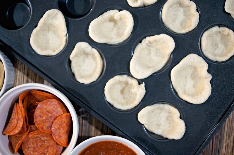 If you’re looking for a delicious, easy to customize appetizer for your next football party or tailgate, try these easy Mini Pizza Bites! You can add whatever toppings you like {think mushrooms, pepperoni, sausage, pineapple, bacon, olives- whatever!} and when you bake them in the Wilton Perfect Results Mega Muffin tin you get 48 of them per batch! That’s one way to win on game day! 