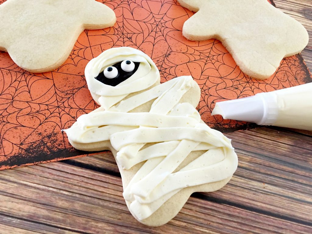These easy DIY Homemade Halloween cookies taste like sugar cookies with a hint of pumpkin- and they are decorated like mummies! While they look super cute, they are easy to make and they’re one of my favorite Halloween recipes for kids.