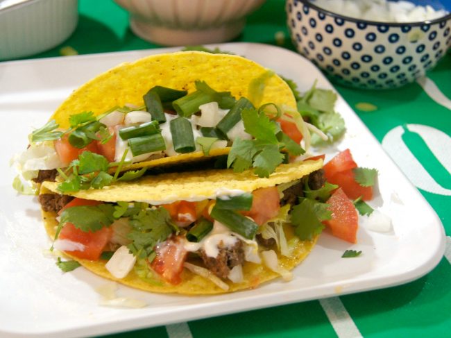 Looking for food recipes and ideas for your next Sunday Football tailgate party? These Game Day Nacho Tacos use ground beef with lots of delicious seasoning and homemade cheese sauce- and of course, they’re loaded with toppings!