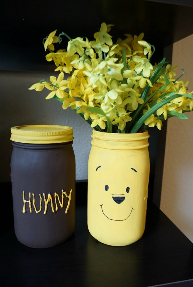 Winnie the Pooh is full of so many adorable characters and memorable quotes- and Disney’s Christopher Robin is sure to be the same! I can’t wait to visit the Hundred Acre Wood again and to celebrate, I made these adorable painted DIY mason jar vases featuring Winnie the Pooh and his Hunny Pot. You could use these vases for flowers, as a centerpiece for a baby shower, or as storage in the nursery for baby keepsakes! The vases can even be repurposed for older kids as bathroom storage!