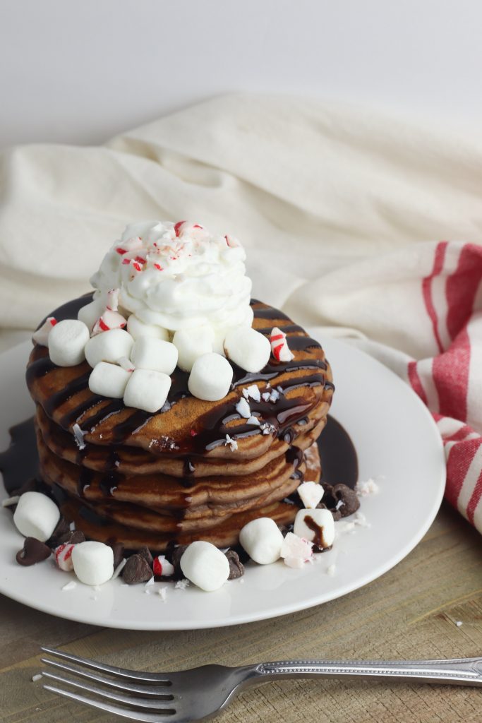 Looking for a delicious easy homemade pancake recipe for a special occasion like Christmas? These fluffy hot cocoa pancakes are made from scratch and garnished with peppermint for kids to enjoy the holidays! 