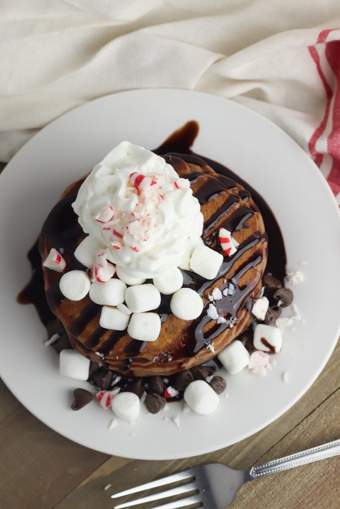 Looking for a delicious easy homemade pancake recipe for a special occasion like Christmas? These fluffy hot cocoa pancakes are made from scratch and garnished with peppermint for kids to enjoy the holidays!
