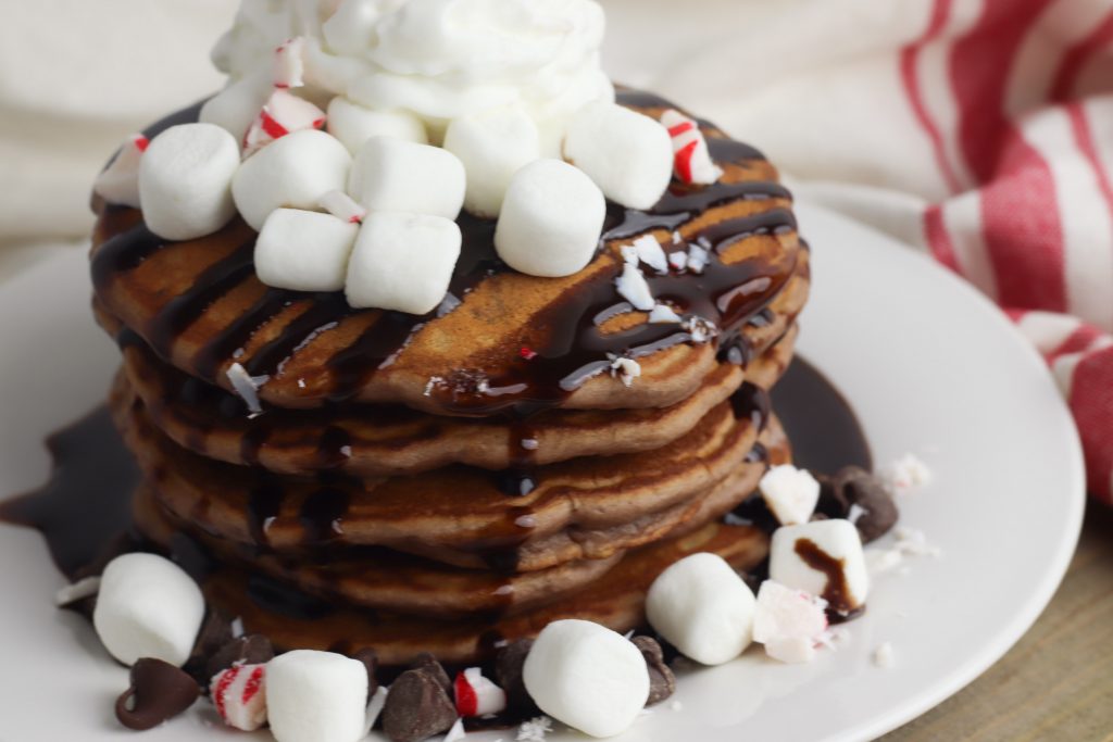 Looking for a delicious easy homemade pancake recipe for a special occasion like Christmas? These fluffy hot cocoa pancakes are made from scratch and garnished with peppermint for kids to enjoy the holidays! 