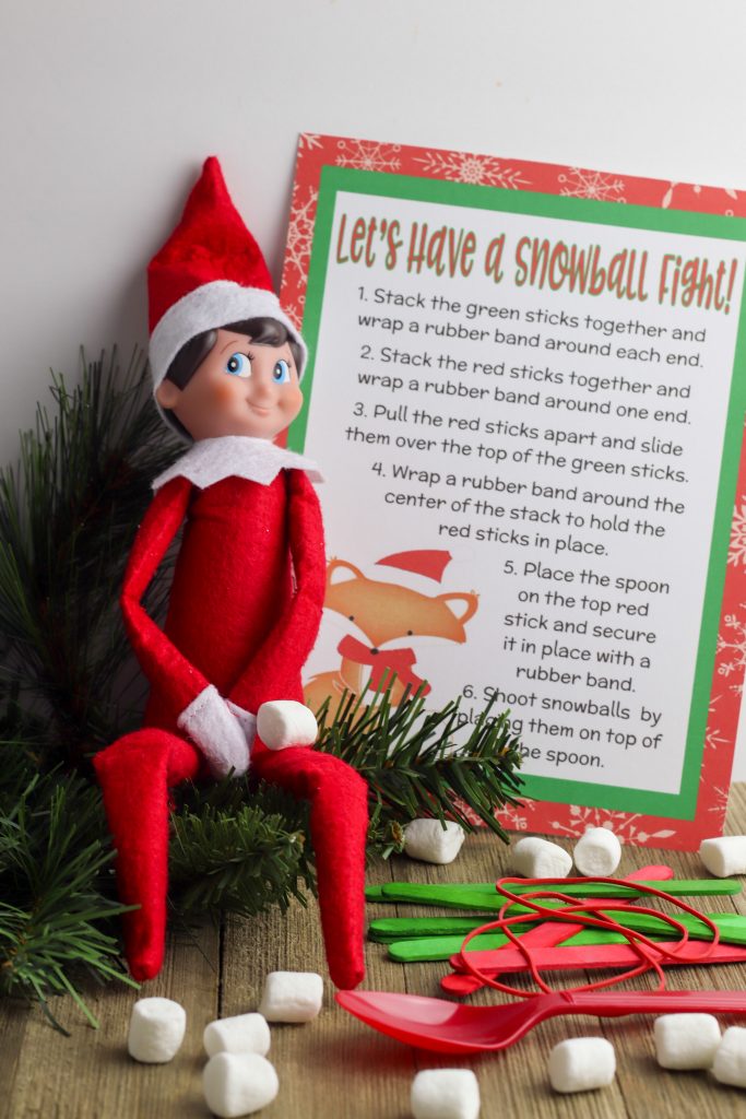 Weeks after their return, Scout Elves start to run out of ideas. Help them keep the fun going for boys or for girls long after their Welcome back arrival day with this new fun and easy Elf on the Shelf Idea- a Snowball Fight with DIY Make Your Own Catapult! The free printable makes it easy for adults- and it’s fun for kids!