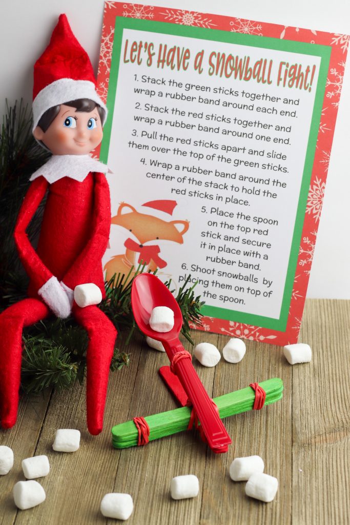 Weeks after their return, Scout Elves start to run out of ideas. Help them keep the fun going for boys or for girls long after their Welcome back arrival day with this new fun and easy Elf on the Shelf Idea- a Snowball Fight with DIY Make Your Own Catapult! The free printable makes it easy for adults- and it’s fun for kids!