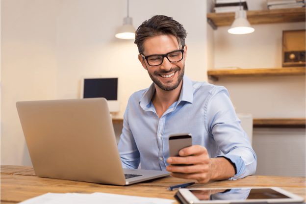 man happily using smartphone in home office