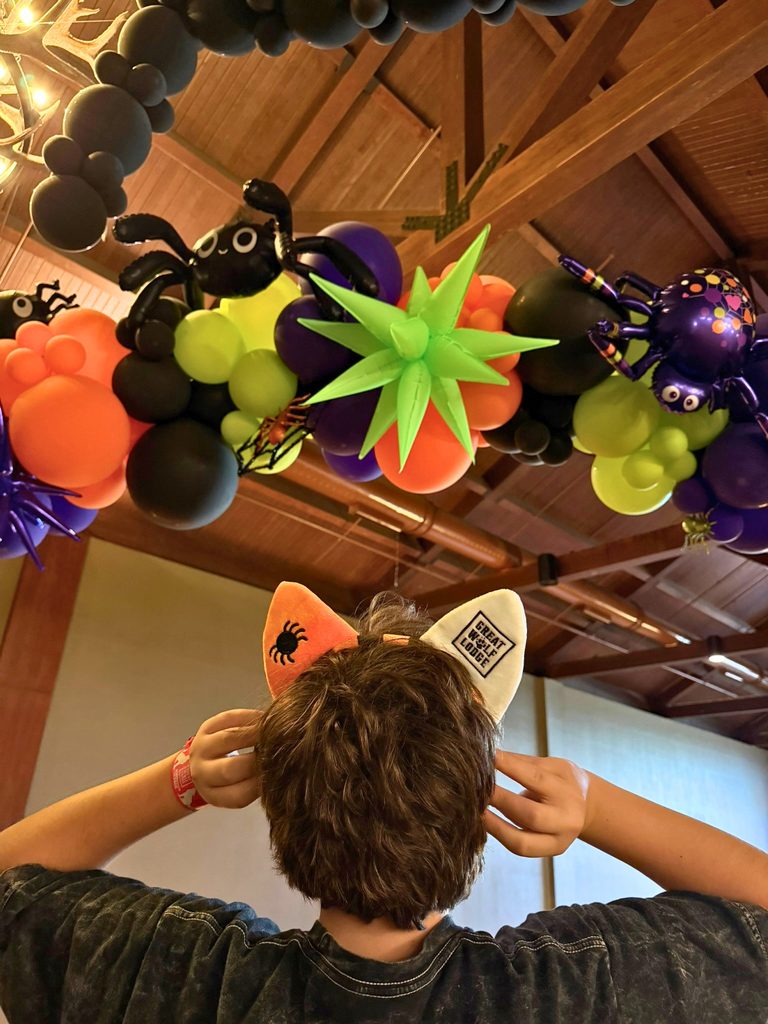 Tween wearing Halloween themed Great Wolf Lodge ears with a themed balloon arch with spider balloons during Howl-O-Ween Must Do Halloween Activities for Kids in Southern California: Great Wolf Lodge Garden Grove Howl-O-Ween