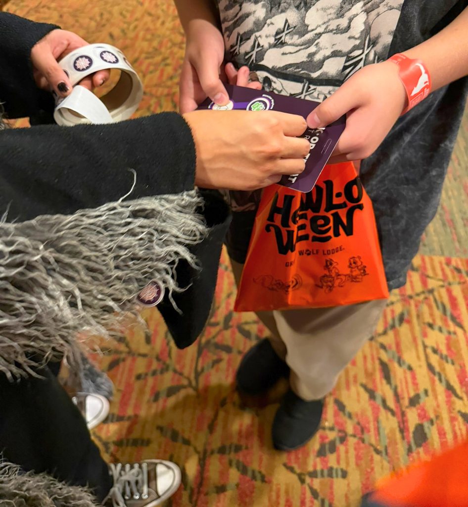 Kid getting a sticker on Trick-or-Treat Trail passport during Great Wolf Lodge Howl-O-Ween